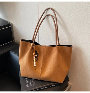 Détail du sac cabas vintage en daim marron avec pendentif en perles de bois