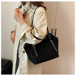 Detail of a large black tote bag showing metal buckles and smooth matte texture finish