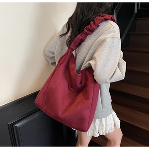 Detail of vintage burgundy tote bag with pleated ruffled strap shown in lifestyle setting