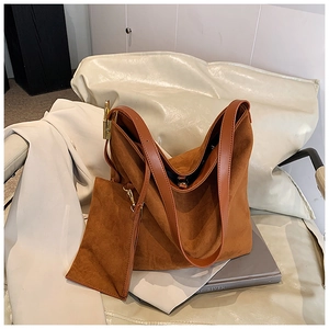Macro shot of dark brown suede tote bag with matching leather pouch on a white sofa