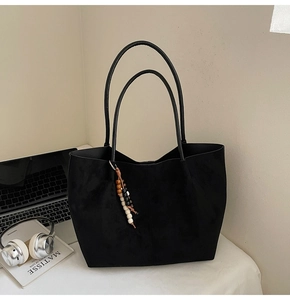 Nahaufnahme der schwarzen matten Shopper-Tasche mit Holzperlen auf minimalistischem Tisch