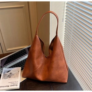 Detail view of large caramel tote bag with lychee grain on dark office desktop