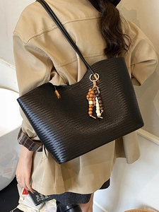 Grand sac cabas en cuir tressé noir avec pompon ethnique porté par un mannequin en intérieur
