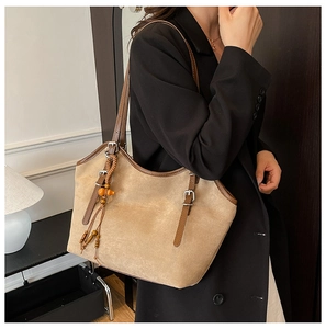 Detail of khaki suede tote bag with brown leather trim and ethnic tassel charm
