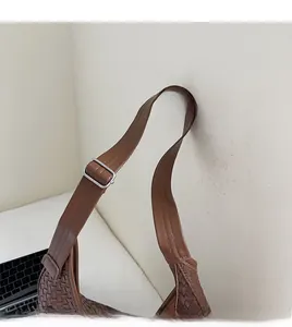 Gros plan d'un sac cabas marron tissé avec bandoulière réglable et boucle en métal argenté