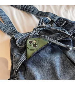 Detail of blue washed denim tote bag showing a front pocket with a green smartphone inside