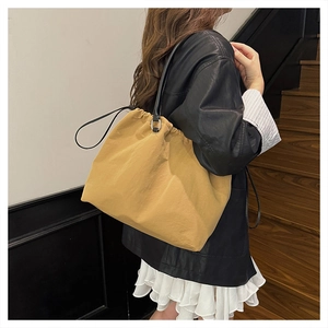 Detail of khaki drawstring tote bag with black leather straps shown in a lifestyle shot