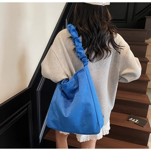 Detail of blue corduroy tote bag with ruffled straps being worn on a staircase