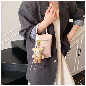 Détail d'un sac à main rose en similicuir avec un charmant ours en peluche et zip doré