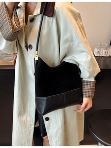 Sac à bandoulière en daim noir avec base en cuir et boucle métallique dorée élégante