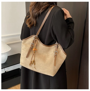 Khaki suede tote bag with brown leather straps and beaded tassel shown on a model