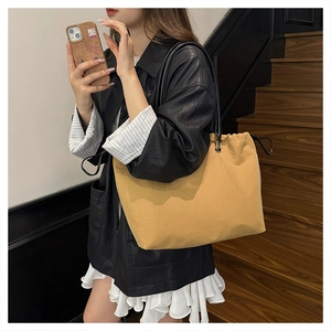 Detail view of large yellow drawstring tote bag with slim black straps and metal buckles