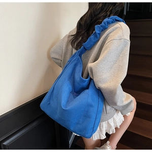 Detail of Klein blue tote bag with a pleated shoulder strap and large front pocket