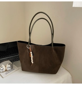 Détail d'un grand sac cabas en daim marron avec anses vertes et pendentif en bois perlé