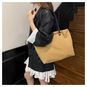 Detailed shot of khaki canvas tote bag with drawstring closure and leather straps