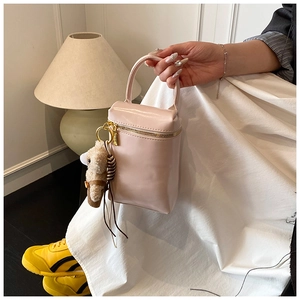 Détail du sac seau rose clair verni avec un charmant ours en peluche attaché à l'anse