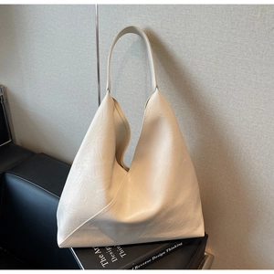 Detail of cream pleated tote bag with faux leather texture on minimalist black book