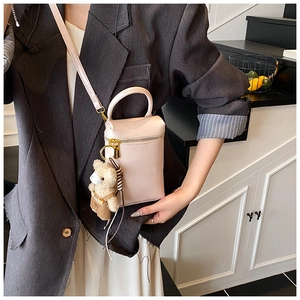 Détail du mini sac boîte rose clair avec breloque ours en peluche porté par le mannequin