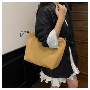 Close-up of ginger yellow drawstring tote bag with smooth texture and black shoulder strap