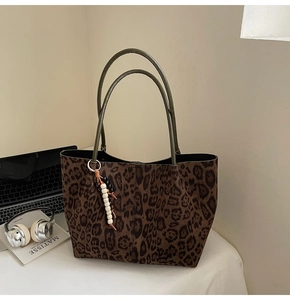 Détail d'un sac cabas léopard avec anses en cuir et pendentif en perles de bois