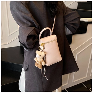 Détail d'un sac à main boîte en cuir rose avec breloque d'ours et poignée élégante