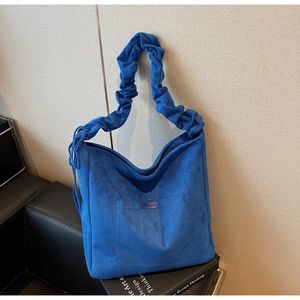 Blue suede tote bag detail featuring gathered cloud-style strap and front patch pocket