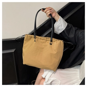 Detail of earthy tote bag featuring drawstring closure and black leather handles