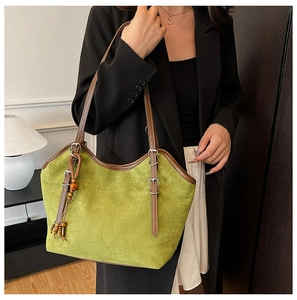 Detail of green suede tote bag with brown leather straps and wooden bead charm detail