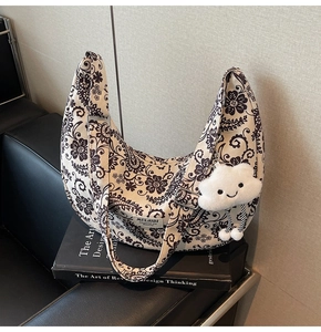 Detail der floralen Paisley-Halbmondtasche mit Plüschwolken-Anhänger und Gurt