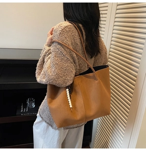 Détail du sac cabas en daim camel avec breloque perlée et bandoulières souples