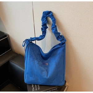 Blue suede tote bag with ruched shoulder strap and large front pocket in retro minimalist style