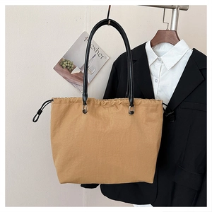 Close-up of khaki nylon tote bag featuring drawstring closure and slim black straps