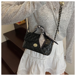 Détail d'un sac bandoulière noir matelassé avec fermoir doré et foulard décoratif