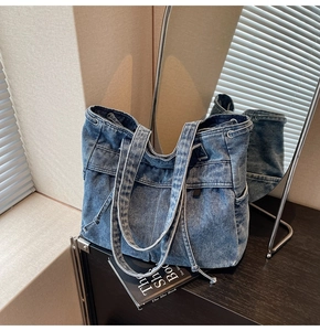 Detail of blue denim tote bag with side drawstring and pockets on a wooden table