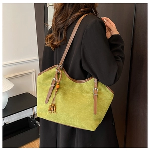 Detail of green suede tote bag with brown leather straps and wooden bead tassel ornament