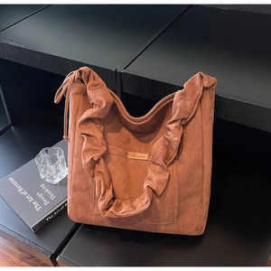 Detail of a brown suede tote bag featuring ruched straps and a minimalist side drawstring
