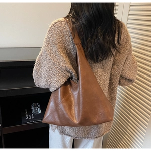 Rear view of model wearing a large brown retro faux leather tote bag in a minimalist setting