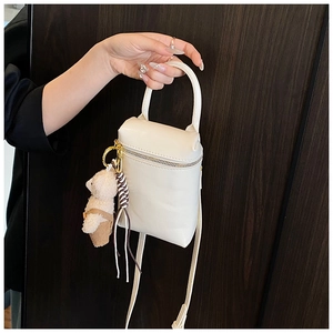 Détail du mini sac bandoulière blanc cassé avec un joli porte-clés ours en peluche