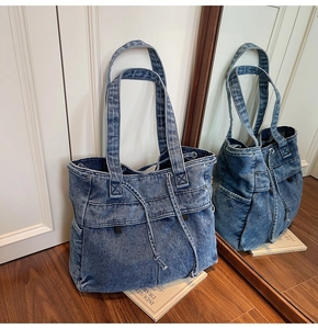 Macro detail of large capacity denim tote bag showing multiple pockets and washed fabric
