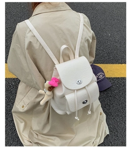 Close-up of a cream mini backpack with silver twist lock and cute plush puppy charm