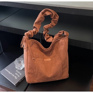 Detail of caramel suede tote bag featuring a creative pleated wide shoulder strap design