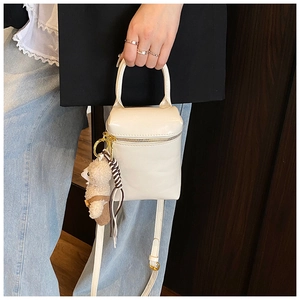 Détail d'un mini sac en cuir blanc avec breloque ours en peluche et franges décoratives