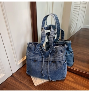 Detail of blue denim tote bag with washed texture and drawstring closure in indoor setting