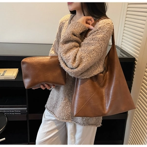 Detail of a brown leather tote bag with matching storage pouch shown in an indoor setting