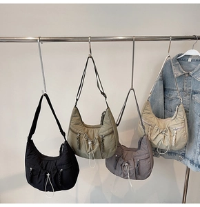 Detailed view of four nylon crossbody bags in black, green, purple and beige with drawstring