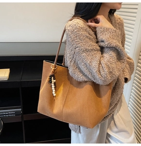 Détail d'un sac cabas en daim marron avec gland perlé et coutures minimalistes