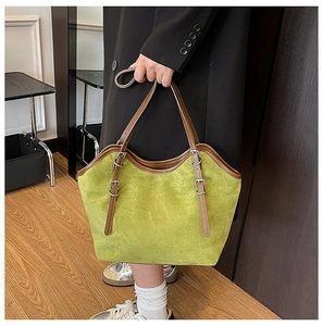 Detail of green suede tote bag with brown leather handles and silver metal hardware