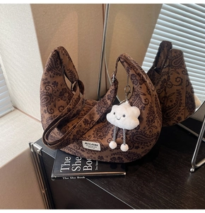 Braune Paisley-Tasche auf schwarzem Buch mit niedlichem Wolken-Plüschanhänger