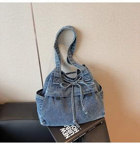 Detail view of washed blue denim tote bag with side pockets and drawstring closure