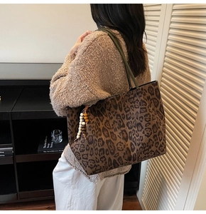 Détail du sac cabas léopard avec anses vert foncé et pompon décoratif en perles de bois